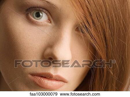 Stock Photo - Woman's face and red hair covering one eye. Fotosearch