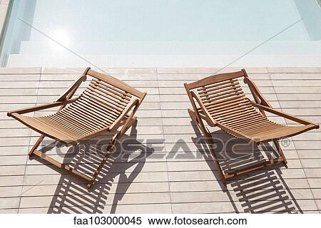 Wooden deck chairs beside pool View Large Photo Image Stock Photography - Wooden deck chairs beside pool. Fotosearch