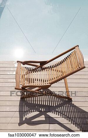 Wooden deckchair beside pool View Large Photo Image Stock Photo - Wooden deckchair beside pool. Fotosearch