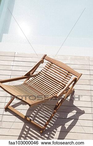 Wooden deckchair beside pool View Large Photo Image Stock Photograph - Wooden deckchair beside pool. Fotosearch