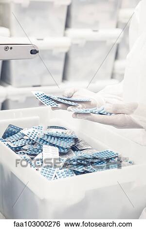 Worker inspecting pill packets exiting production equipment View Large Photo Image Stock Photograph - Worker inspecting pill packets exiting production equipment. Fotosearch
