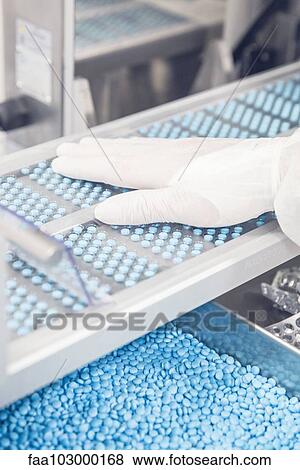 Worker monitoring pill trays moving along conveyor belt through packaging machine View Large Photo Image Stock Photo - Worker monitoring pill trays moving along conveyor belt through packaging machine. Fotosearch
