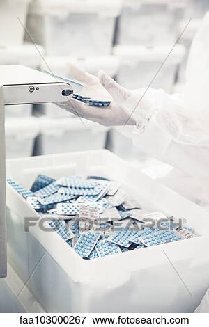 Worker packaging pill packets exiting production equipment View Large Photo Image Stock Photo - Worker packaging pill packets exiting production equipment. Fotosearch