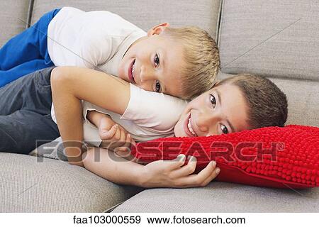 Young brothers lying together on sofa View Large Photo Image Stock Photo - Young brothers lying together on sofa. Fotosearch