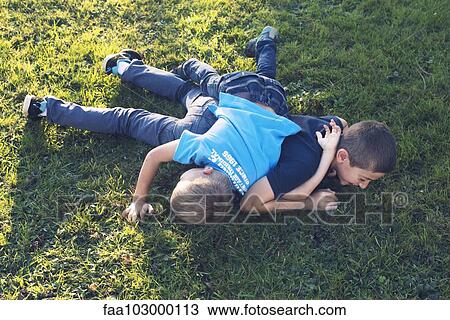 Stock Image - Young brothers playing together on lawn. Fotosearch