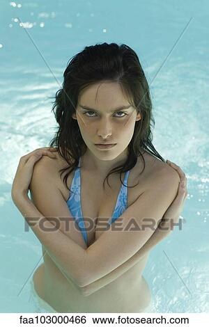 Stock Photograph - "Young woman in pool with arms folded over chest, portrait". Fotosearch