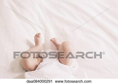 Baby lying on bed, cropped View Large Photo Image Stock Image - Baby lying on bed, cropped. Fotosearch