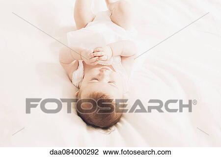 Baby lying on bed playing View Large Photo Image Stock Image - Baby lying on bed playing. Fotosearch