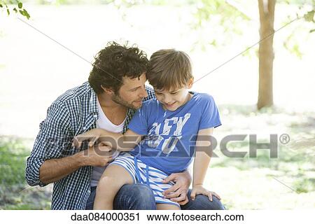 Boy sitting on father's lap View Large Photo Image Stock Image - Boy sitting on father's lap. Fotosearch