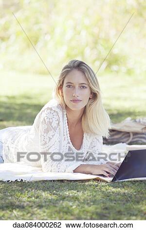 Stock Image - College student using laptop outdoors. Fotosearch