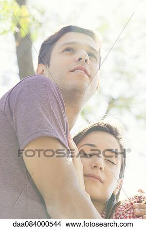 Couple embracing outdoors, low angle view View Large Photo Image Picture - Couple embracing outdoors, low angle view. Fotosearch