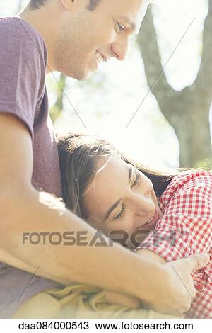 Couple embracing outdoors, woman resting head on man's lap View Large Photo Image Stock Image - Couple embracing outdoors, woman resting head on man's lap. Fotosearch