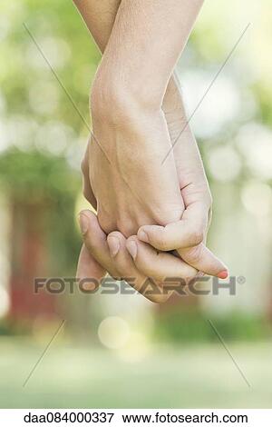Couple holding hands outdoors, cropped rear view View Large Photo Image Stock Photo - Couple holding hands outdoors, cropped rear view. Fotosearch