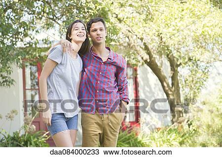Couple standing together outdoors with arms around each other's shoulders View Large Photo Image Stock Image - Couple standing together outdoors with arms around each other's shoulders. Fotosearch