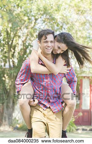 Couple together outdoors, man giving woman a piggyback ride View Large Photo Image Stock Photography - Couple together outdoors, man giving woman a piggyback ride. Fotosearch