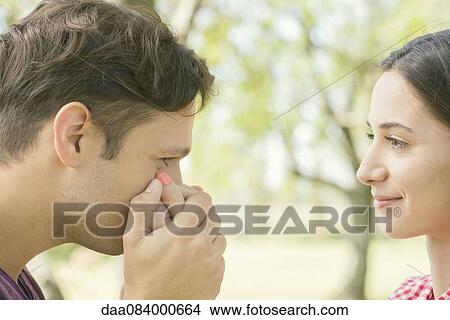 Picture - Couple together outdoors, man kissing woman's hand. Fotosearch