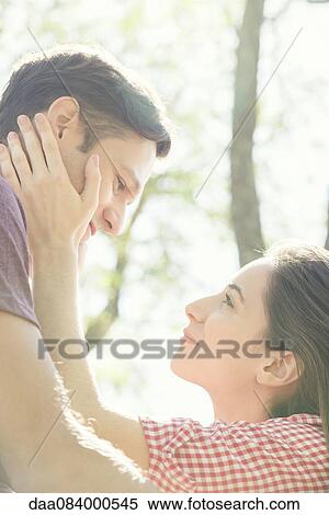 Couple together outdoors, woman holding man's face in her hands View Large Photo Image Stock Photography - Couple together outdoors, woman holding man's face in her hands. Fotosearch