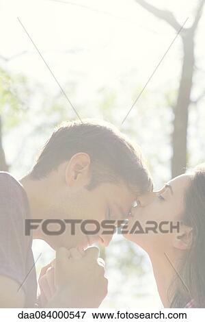 Couple together outdoors, woman kissing man's forehead View Large Photo Image Stock Photo - Couple together outdoors, woman kissing man's forehead. Fotosearch