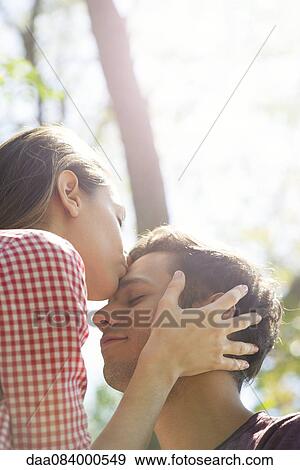 Couple together outdoors, woman kissing man's forehead View Large Photo Image Stock Photo - Couple together outdoors, woman kissing man's forehead. Fotosearch
