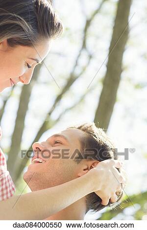 Stock Image - Couple together outdoors, woman stroking man's hair. Fotosearch