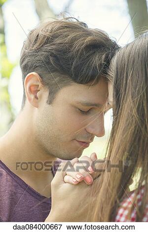 Couple touching foreheads and holding hands outdoors View Large Photo Image Stock Photo - Couple touching foreheads and holding hands outdoors. Fotosearch