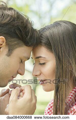 Couple touching foreheads and holding hands outdoors View Large Photo Image Stock Photo - Couple touching foreheads and holding hands outdoors. Fotosearch