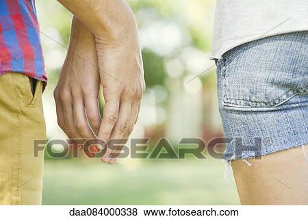 Couple touching hands outdoors, cropped rear view View Large Photo Image Stock Photo - Couple touching hands outdoors, cropped rear view. Fotosearch