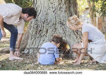 Stock Photography - Family discovering hollow tree trunk. Fotosearch