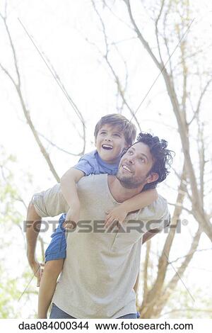 Father carrying young son piggyback View Large Photo Image Picture - Father carrying young son piggyback. Fotosearch