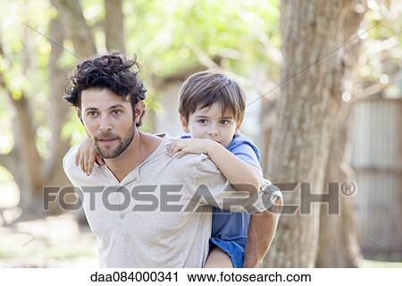 Stock Image - Father carrying young son piggyback. Fotosearch