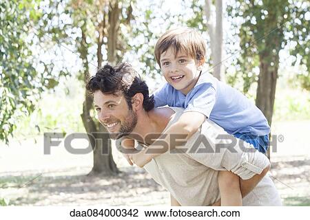 Stock Image - Father carrying young son piggyback. Fotosearch