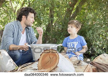 Stock Photograph - Father with young son chatting together outdoors. Fotosearch