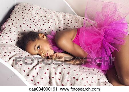 Stock Image - Girl lying on bed in tutu. Fotosearch