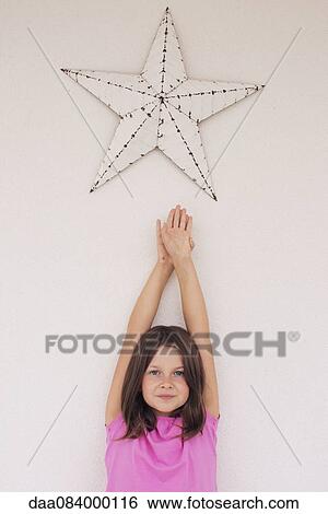 Girl reaching toward star shape hanging above her head, portrait View Large Photo Image Stock Photograph - Girl reaching toward star shape hanging above her head, portrait. Fotosearch