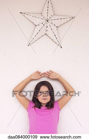 Girl standing beneath star decoration, daydreaming, portrait View Large Photo Image Stock Photo - Girl standing beneath star decoration, daydreaming, portrait. Fotosearch