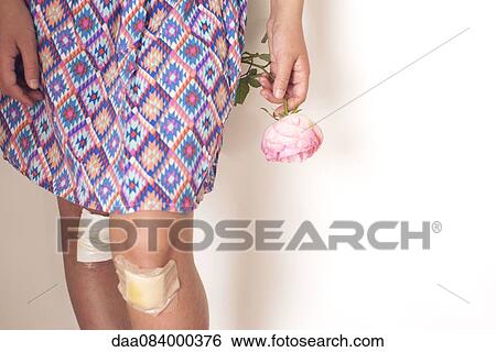 Stock Photograph - Girl with bandaged knees holding rose, cropped. Fotosearch