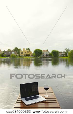 Laptop computer and wine glass on lake pier View Large Photo Image Stock Image - Laptop computer and wine glass on lake pier. Fotosearch