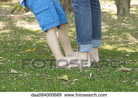 Stock Photo - Little boy standing barefoot on father's feet, cropped. Fotosearch
