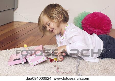 Picture - Little girl removing necklace from jewellery box. Fotosearch