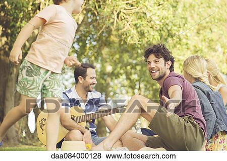 Stock Photo - Man at picnic watching children play. Fotosearch