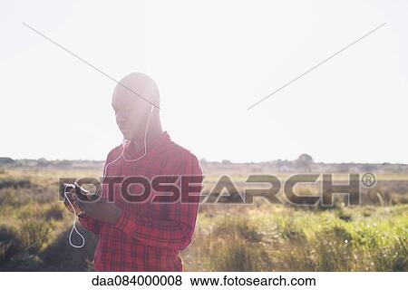 Man listening to music with earphones outdoors View Large Photo Image Stock Photo - Man listening to music with earphones outdoors. Fotosearch