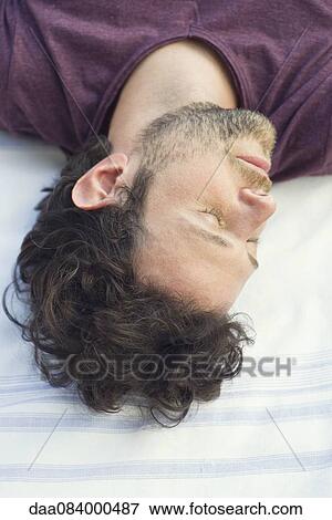 Stock Photo - Man napping outdoors. Fotosearch