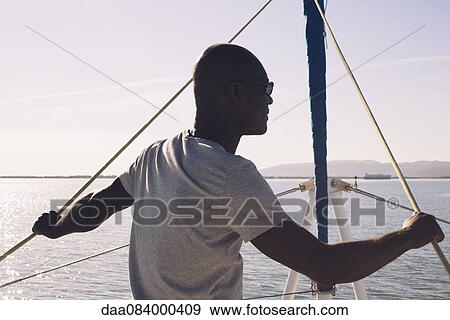Man on sail boat, looking at view View Large Photo Image Stock Photo - Man on sail boat, looking at view. Fotosearch