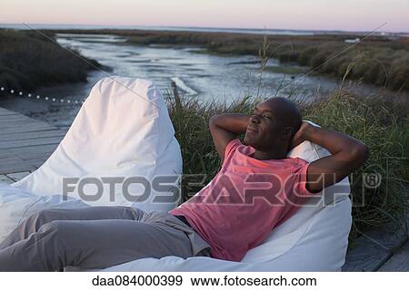 Man relaxing at water's edge View Large Photo Image Stock Photo - Man relaxing at water's edge. Fotosearch