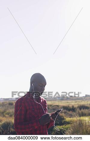 Man using smartphone and earphones outdoors View Large Photo Image Stock Photo - Man using smartphone and earphones outdoors. Fotosearch