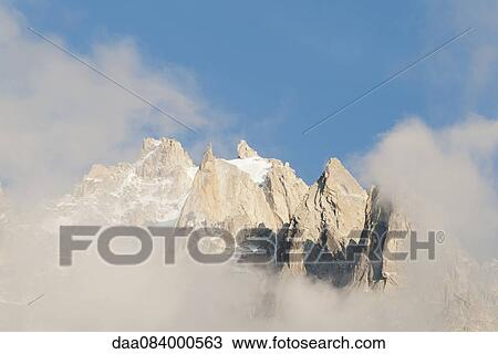 Stock Image - Mountain peaks surrounded by clouds. Fotosearch