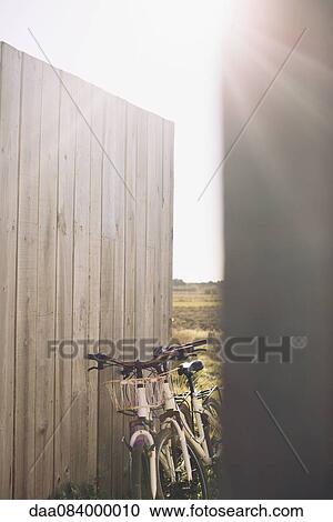 Pair of bicycles leaning against wooden fence View Large Photo Image Stock Image - Pair of bicycles leaning against wooden fence. Fotosearch