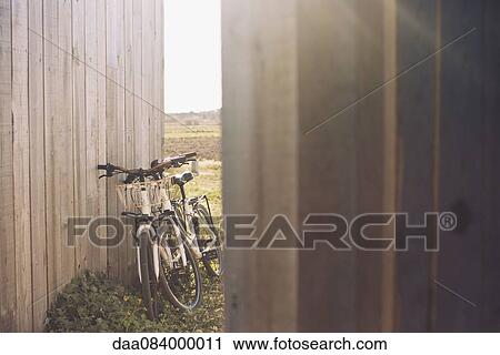 Pair of bicycles leaning against wooden fence View Large Photo Image Stock Image - Pair of bicycles leaning against wooden fence. Fotosearch