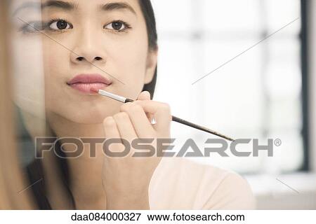 Woman applying lipstick View Large Photo Image Stock Photo - Woman applying lipstick. Fotosearch