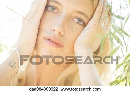 Stock Image - Woman holding head, portrait. Fotosearch